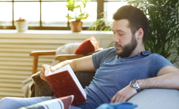 man is reading a book in the coach